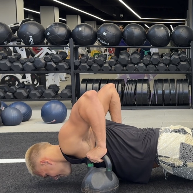 Swimmer performing a kettlebell core exercise in the gym
