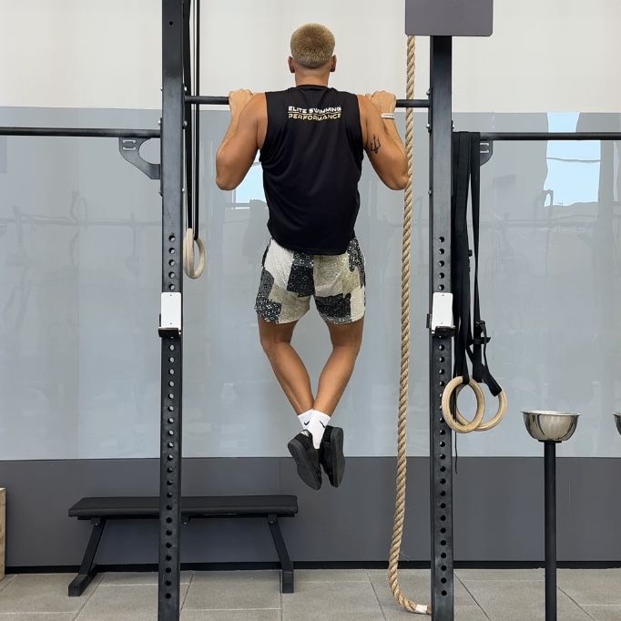 Swimmer performing weighted pull-ups on a rack
